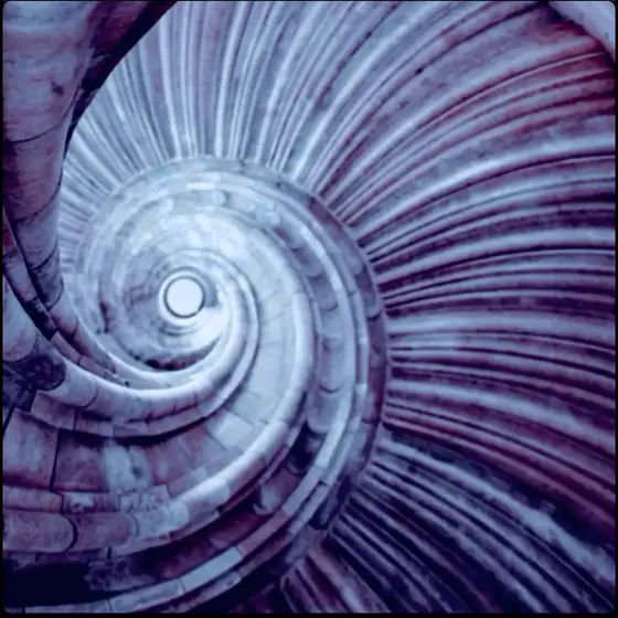 A stone spiral staircase photographed from above, curving inward.